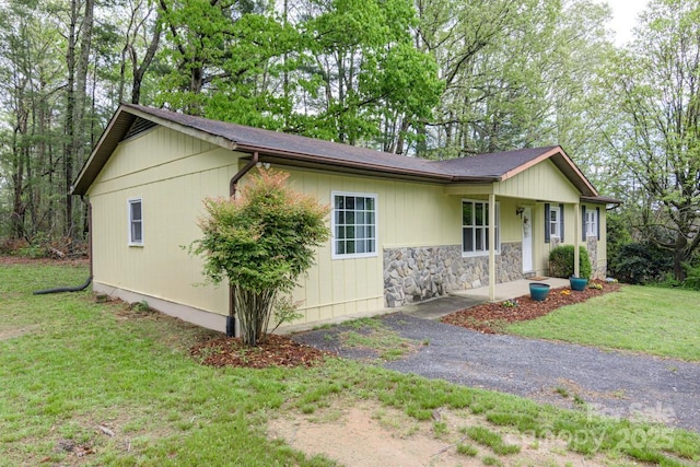 ranch-style home with a front lawn and stone siding