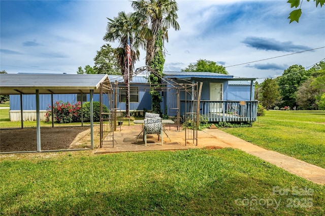 rear view of property featuring a lawn, a patio area, a deck, and metal roof