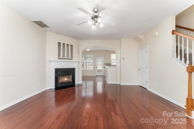 827 Gentlewinds Ct, Fort Mill, SC 29708 - unfurnished living room featuring visible vents, a fireplace with flush hearth, wood finished floors, ceiling fan, and arched walkways