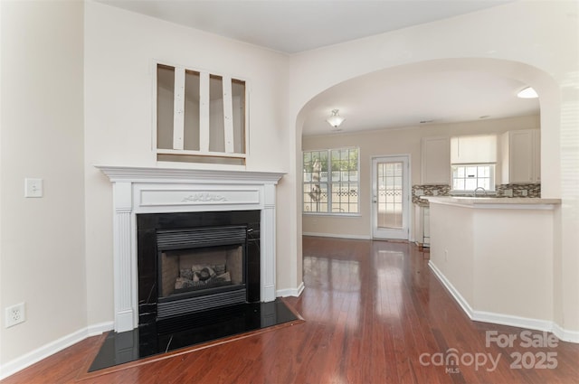 827 Gentlewinds Ct, Fort Mill, SC 29708 - unfurnished living room with baseboards, arched walkways, dark wood finished floors, and a fireplace with flush hearth