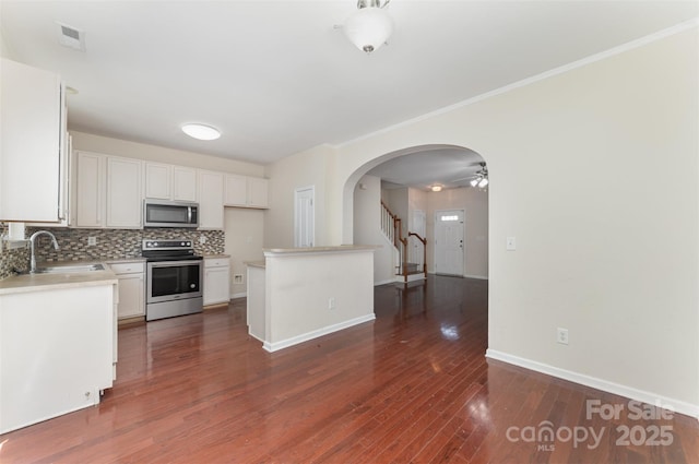 827 Gentlewinds Ct, Fort Mill, SC 29708 - kitchen with white cabinets, a sink, arched walkways, stainless steel appliances, and decorative backsplash