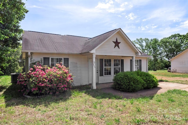 view of front of house with a shingled roof, a front lawn, and cooling unit