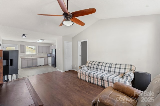 living room with baseboards, vaulted ceiling, a ceiling fan, and light wood-style flooring