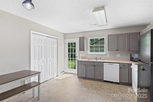 kitchen featuring light countertops, gray cabinetry, a sink, and black appliances