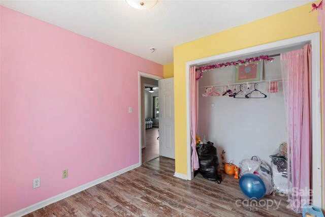 unfurnished bedroom featuring wood finished floors, a closet, and baseboards