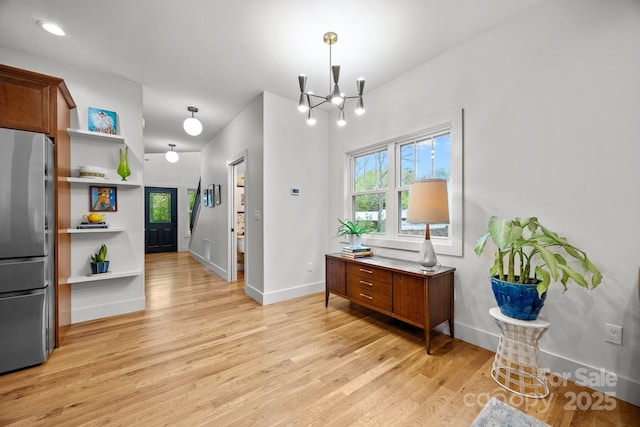 interior space featuring baseboards, an inviting chandelier, and light wood finished floors