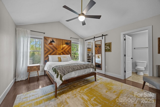 bedroom featuring lofted ceiling, a barn door, wood finished floors, and multiple windows