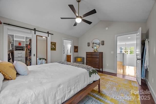 bedroom with a walk in closet, a ceiling fan, wood finished floors, a barn door, and lofted ceiling