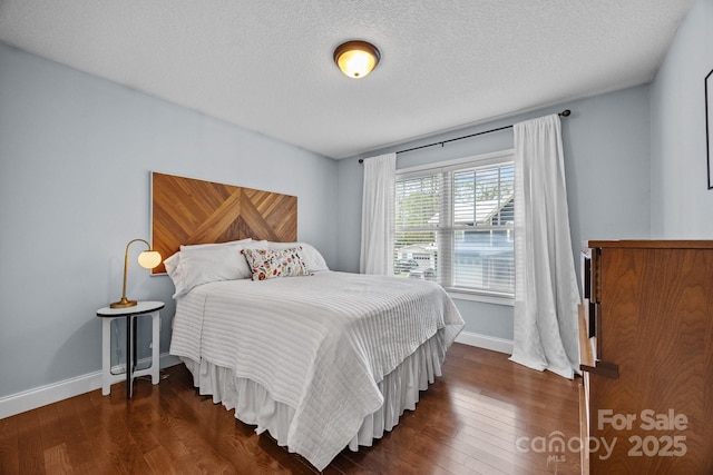 bedroom with baseboards, a textured ceiling, and dark wood finished floors