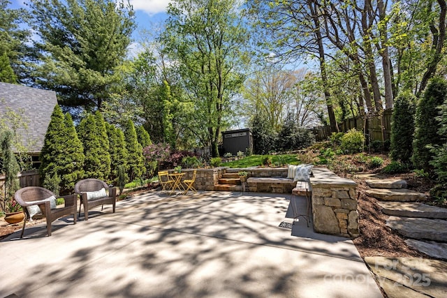view of patio / terrace featuring a fenced backyard, an outbuilding, and a storage shed