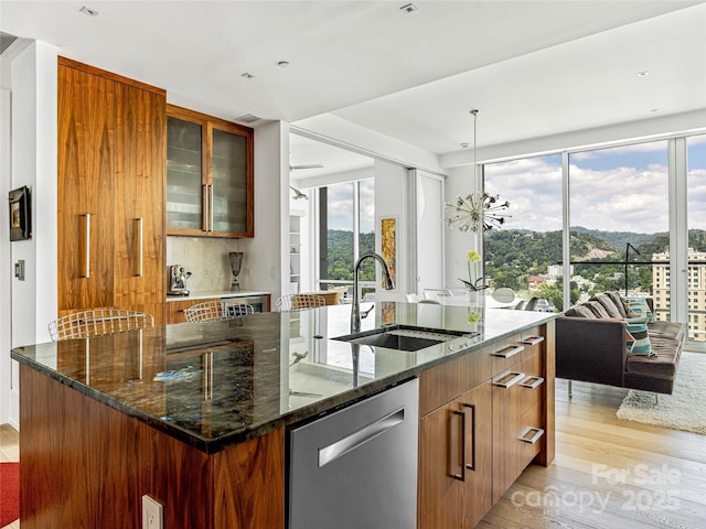 7 Patton Ave Unit 1503, Asheville, NC 28801 - kitchen with stainless steel dishwasher, light wood-style floors, an island with sink, and dark stone counters