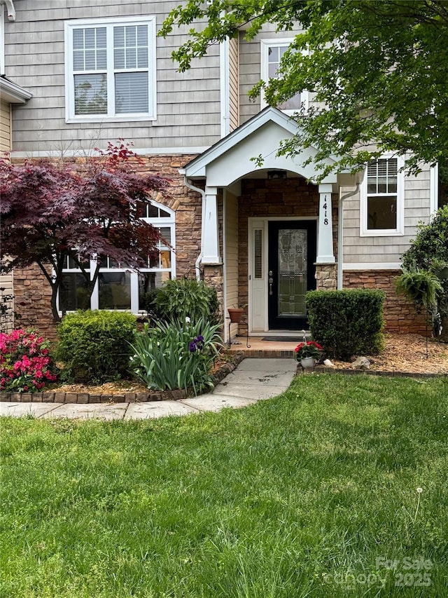 doorway to property with a lawn and stone siding