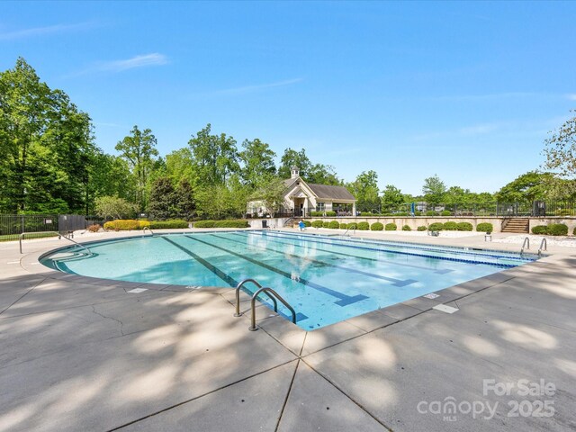 community pool with a patio area and fence