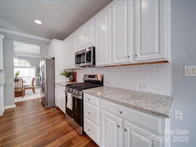 7642 Horseshoe Creek Dr, Huntersville, NC 28078 - kitchen featuring wood finished floors, stainless steel appliances, white cabinetry, backsplash, and ornamental molding