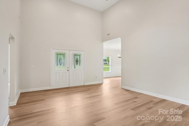 entrance foyer featuring a high ceiling, light wood finished floors, and baseboards