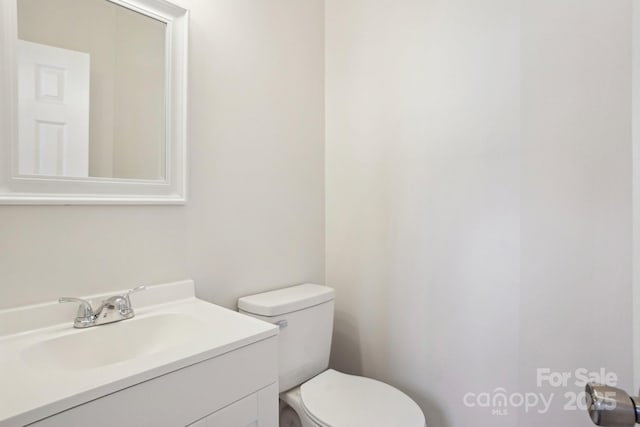 half bathroom with vanity and toilet