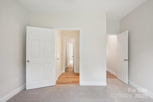 unfurnished bedroom with light carpet and baseboards