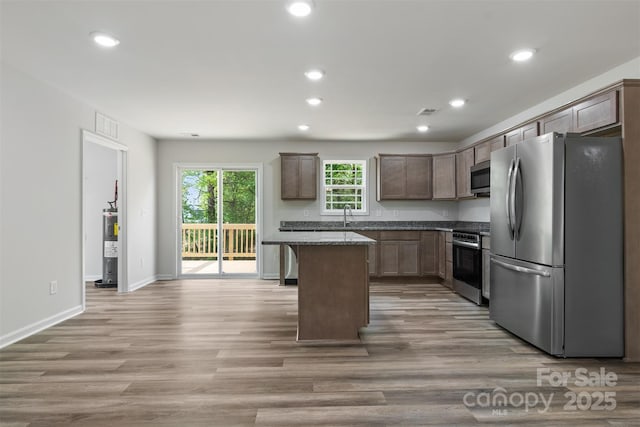kitchen with light wood-style floors, a center island, recessed lighting, a sink, and stainless steel appliances