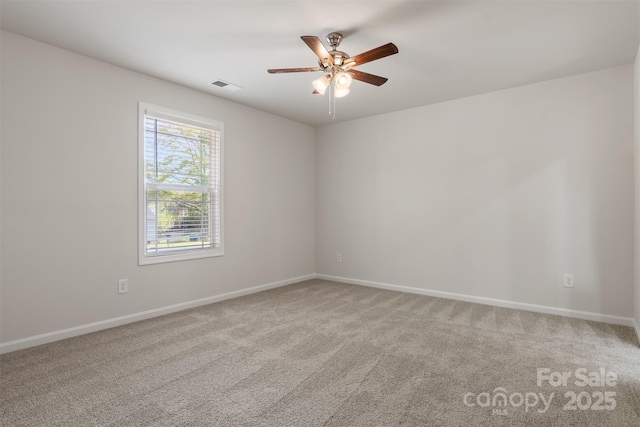 carpeted spare room featuring visible vents, a ceiling fan, and baseboards