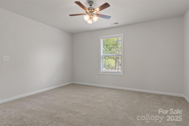 carpeted empty room with baseboards, visible vents, and ceiling fan