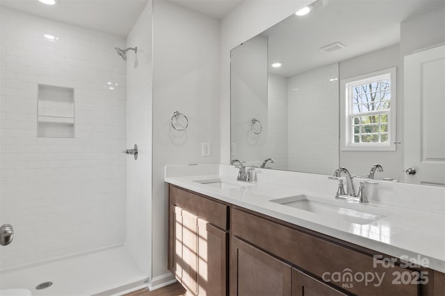 bathroom featuring a sink, a tile shower, recessed lighting, and double vanity