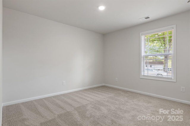 empty room with baseboards, visible vents, and light colored carpet