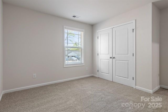 unfurnished bedroom featuring carpet flooring, baseboards, visible vents, and a closet