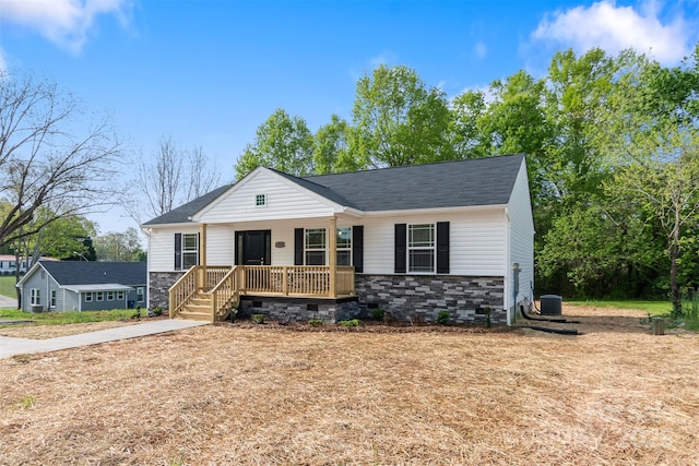 view of front of home with covered porch, a shingled roof, central AC unit, and stone siding