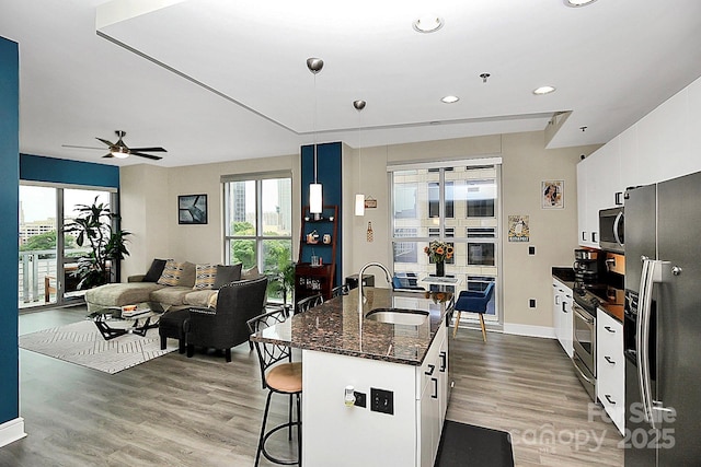 kitchen featuring a sink, appliances with stainless steel finishes, a kitchen breakfast bar, and light wood finished floors