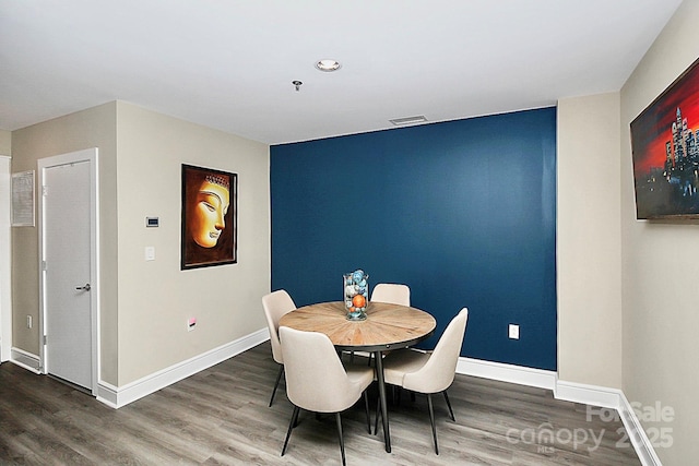 dining space featuring baseboards, wood finished floors, and visible vents