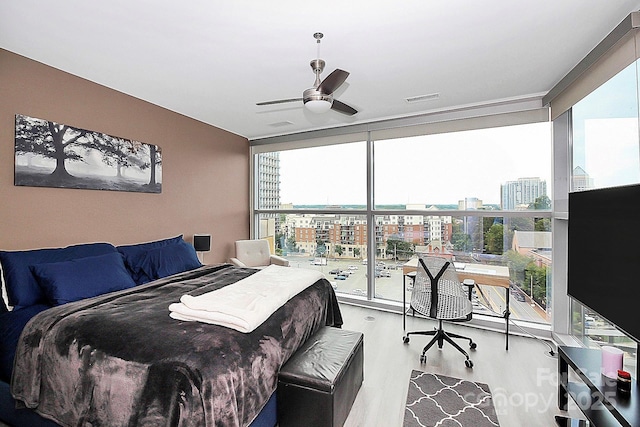bedroom featuring visible vents, floor to ceiling windows, wood finished floors, and multiple windows