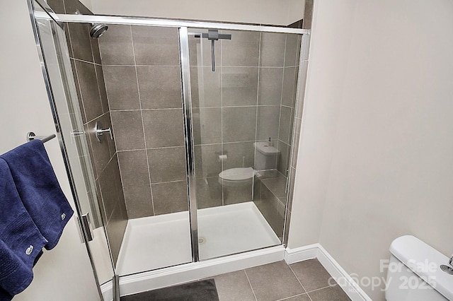 bathroom with tile patterned floors, baseboards, a shower stall, and toilet