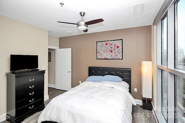 bedroom with baseboards, visible vents, and wood finished floors