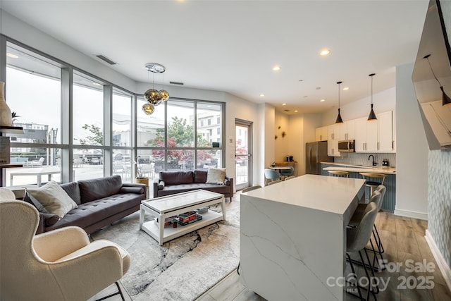 living room with recessed lighting, visible vents, a chandelier, and light wood-style floors