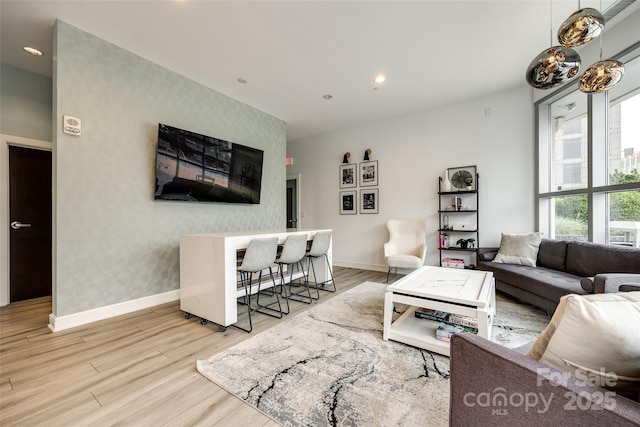 living room with baseboards, an accent wall, and wallpapered walls