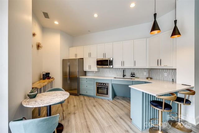 kitchen with white cabinets, a sink, light countertops, stainless steel appliances, and visible vents