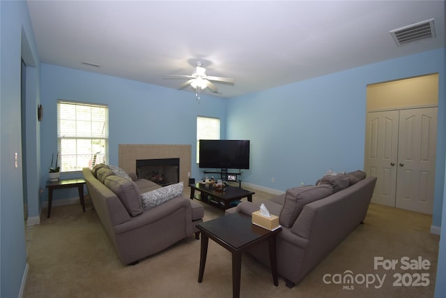 living area featuring plenty of natural light, visible vents, ceiling fan, and light colored carpet