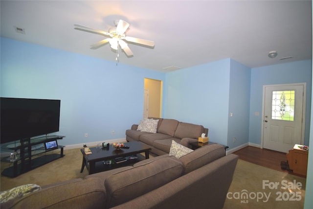 living area featuring baseboards, a ceiling fan, and visible vents