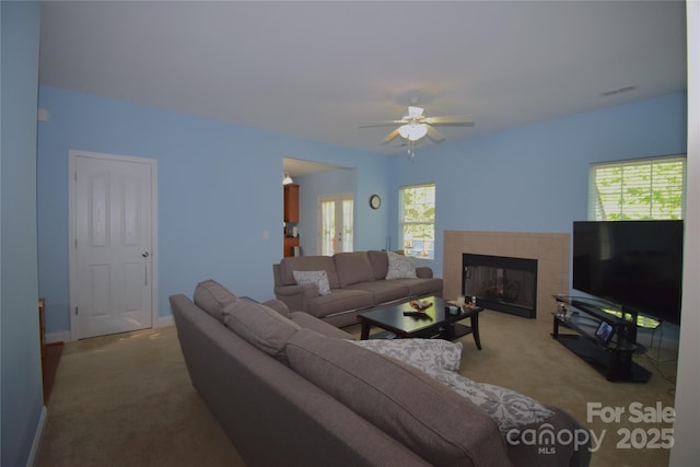 carpeted living room featuring a tiled fireplace, visible vents, baseboards, and ceiling fan