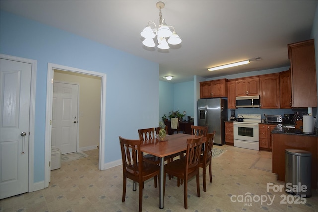 dining space featuring light floors, baseboards, a toaster, and an inviting chandelier