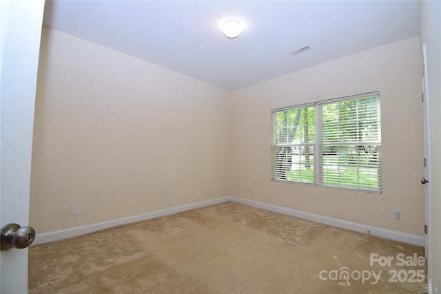 empty room with carpet floors, visible vents, and baseboards