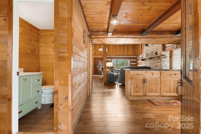 kitchen with wooden ceiling, beamed ceiling, dark wood-type flooring, and wooden walls
