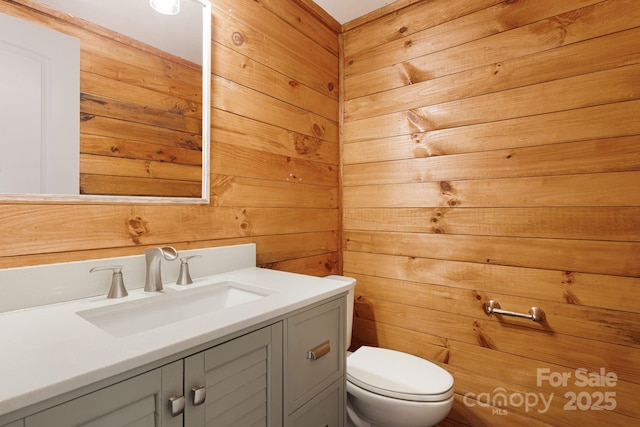 half bath featuring wood walls, toilet, and vanity