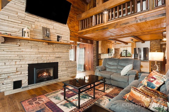 living room featuring wood ceiling, hardwood / wood-style flooring, beamed ceiling, wooden walls, and a stone fireplace