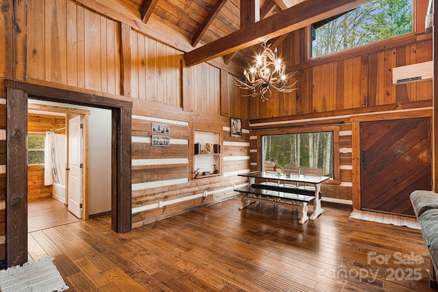 sitting room with high vaulted ceiling, a chandelier, beamed ceiling, wood walls, and a wall unit AC
