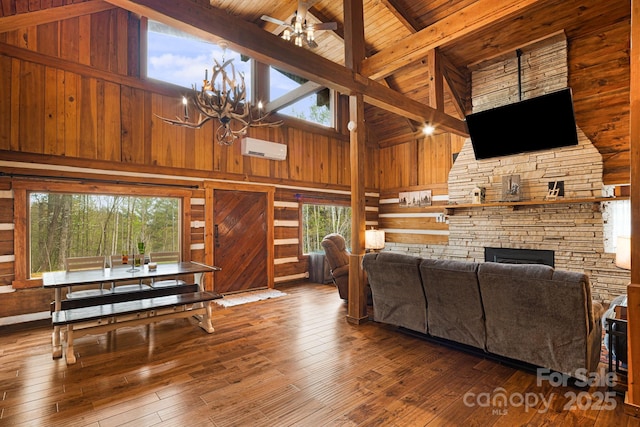 living area featuring a chandelier, beamed ceiling, wooden walls, a stone fireplace, and high vaulted ceiling