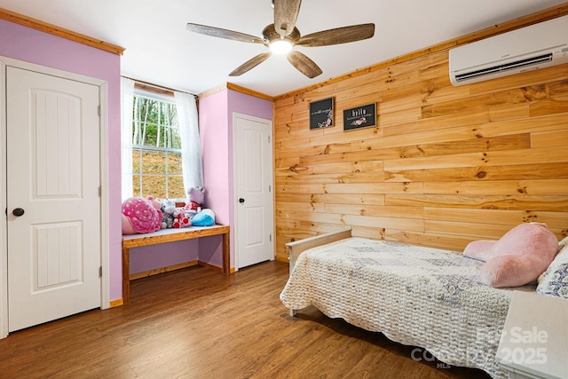 bedroom featuring ornamental molding, wooden walls, wood finished floors, and an AC wall unit