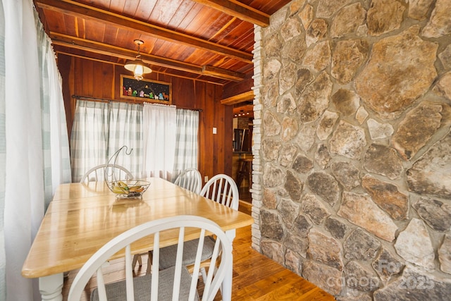 dining space with beamed ceiling, wooden walls, wooden ceiling, and hardwood / wood-style flooring