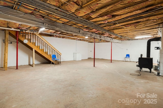 unfinished below grade area featuring a wood stove and stairs
