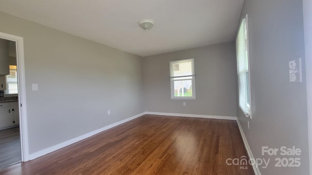 empty room with dark wood finished floors and baseboards